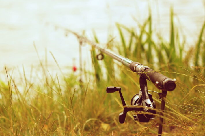 Wędka z kołowrotkiem przygotowana do połowu nad brzegiem wody - wędkowanie dla początkujących i nauka podstawowych technik łowienia ryb.